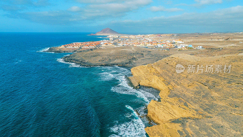 Aerial view of the coast in the natural reserve of "Montaña Pelada" and town of El Medano in the background. Tenerife, Canary Islands. Drone shot